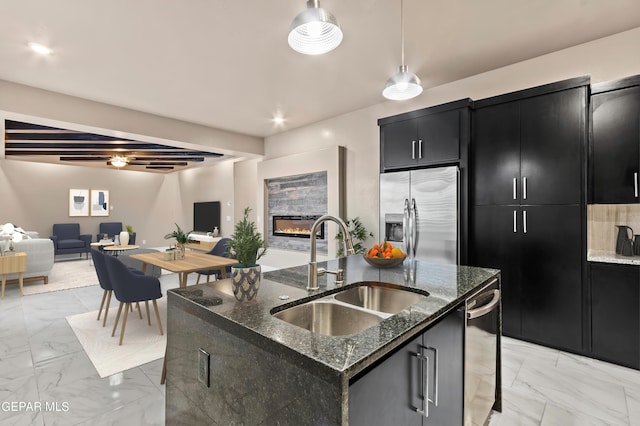 kitchen featuring stainless steel fridge with ice dispenser, a center island with sink, beamed ceiling, pendant lighting, and sink