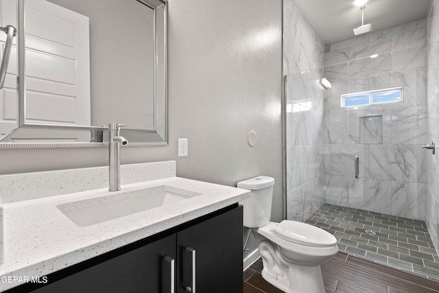 bathroom with toilet, a shower with door, and vanity