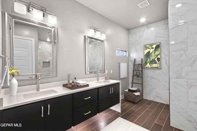 bathroom with tiled shower and vanity