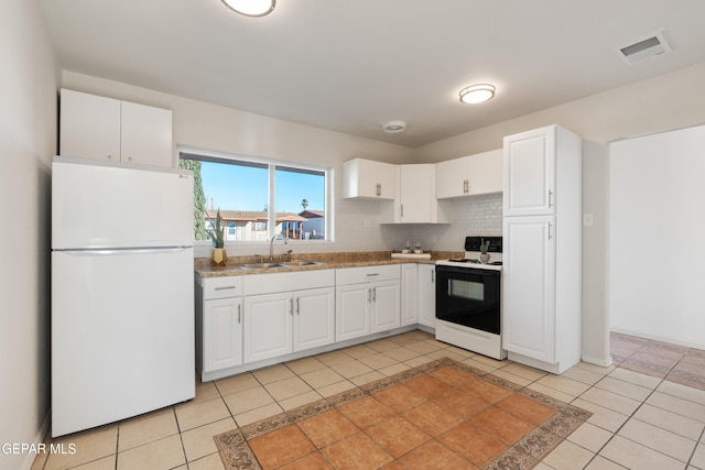 kitchen with electric range oven, sink, light tile patterned flooring, white cabinets, and white refrigerator