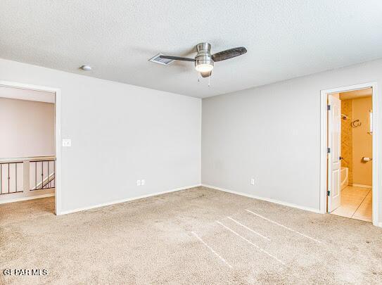 unfurnished room featuring ceiling fan, light colored carpet, and a textured ceiling