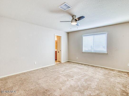 carpeted spare room featuring a textured ceiling and ceiling fan