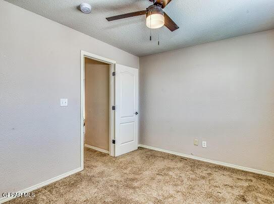 unfurnished room with ceiling fan, light colored carpet, and a textured ceiling