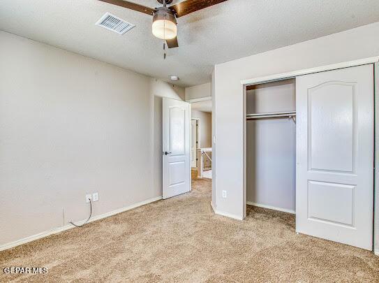 unfurnished bedroom featuring ceiling fan, a closet, and light carpet