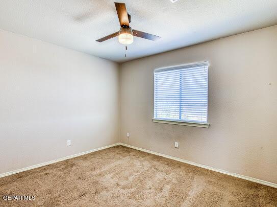 carpeted spare room featuring ceiling fan