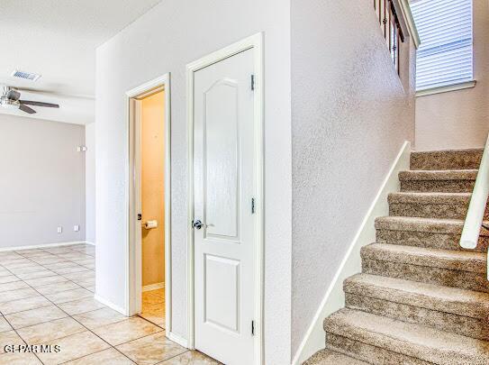 staircase with ceiling fan and tile patterned flooring