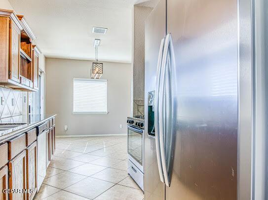 kitchen featuring light tile patterned floors, appliances with stainless steel finishes, pendant lighting, and decorative backsplash