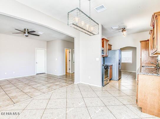 kitchen with sink, ceiling fan with notable chandelier, stainless steel appliances, and light tile patterned flooring