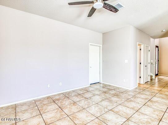 empty room featuring a textured ceiling, ceiling fan, and light tile patterned flooring