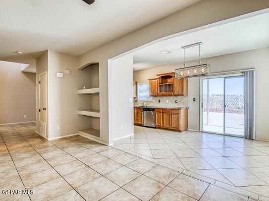 kitchen featuring tasteful backsplash, dishwasher, pendant lighting, light tile patterned floors, and built in shelves