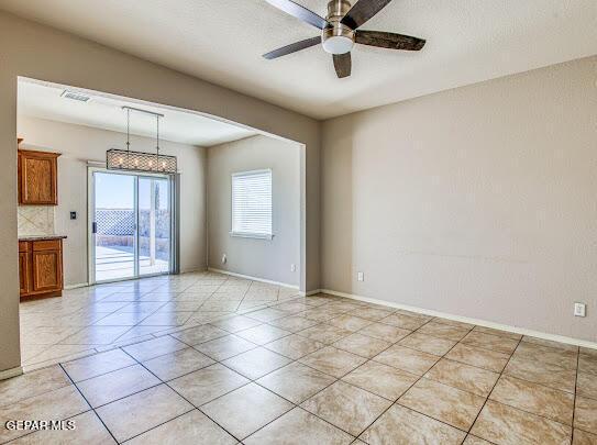 tiled empty room featuring ceiling fan