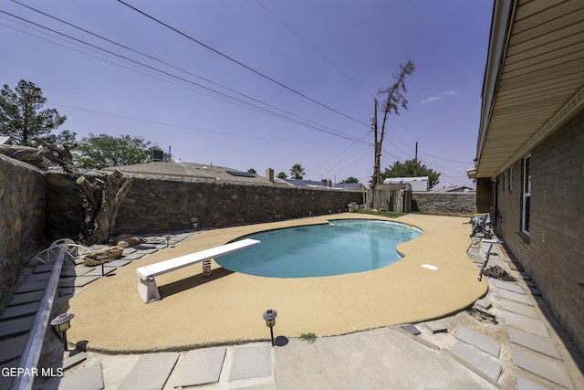 view of swimming pool featuring a diving board and a patio