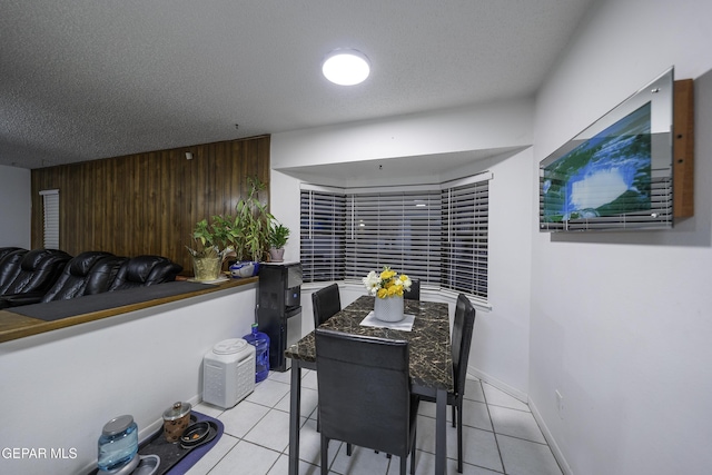 tiled dining room featuring wood walls and a textured ceiling