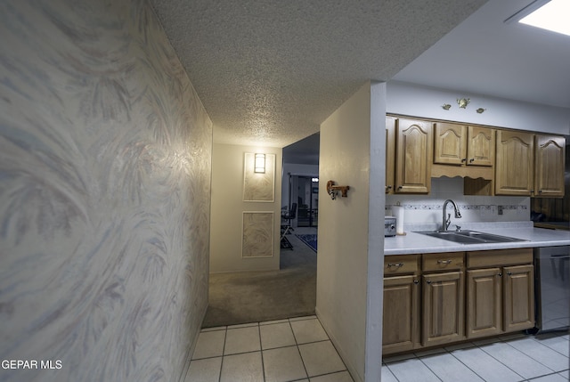 kitchen featuring sink, dishwashing machine, a textured ceiling, and light tile patterned flooring