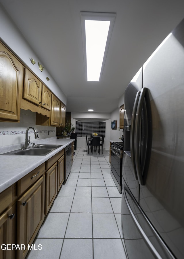 kitchen with dishwasher, gas range oven, sink, stainless steel fridge, and light tile patterned floors