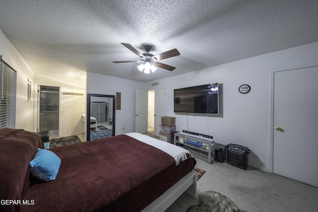 bedroom with ceiling fan, a textured ceiling, connected bathroom, and carpet flooring