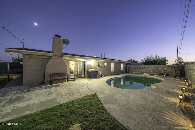 pool at dusk with a patio area