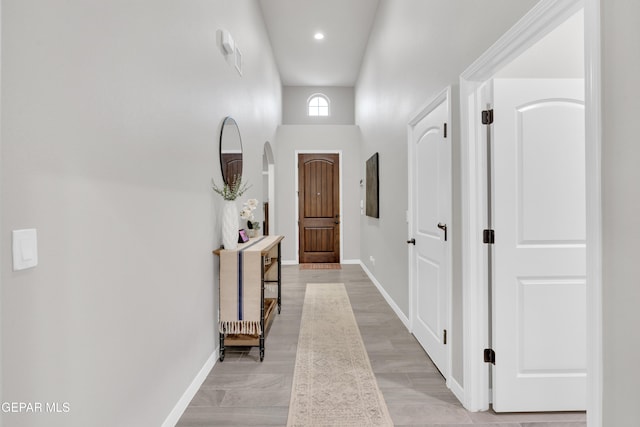 corridor with a high ceiling and light hardwood / wood-style flooring