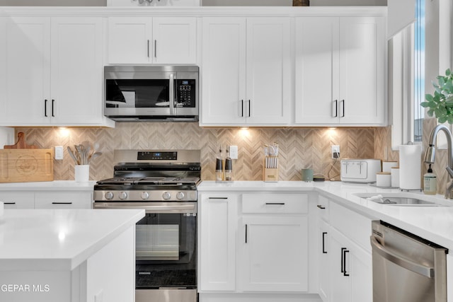 kitchen with backsplash, appliances with stainless steel finishes, sink, and white cabinets