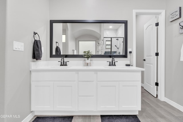 bathroom with hardwood / wood-style flooring, vanity, and an enclosed shower