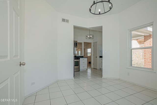 spare room with light tile patterned floors and an inviting chandelier