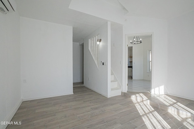 spare room featuring an AC wall unit and an inviting chandelier