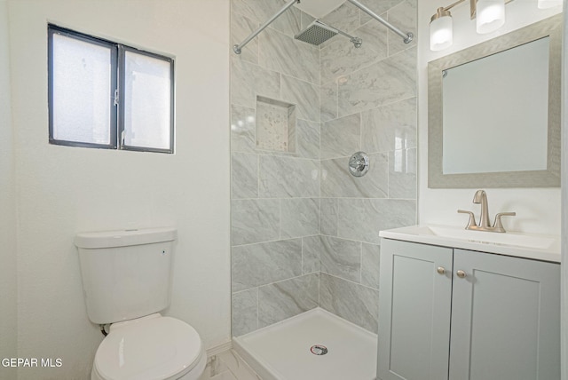 bathroom with toilet, vanity, and tiled shower