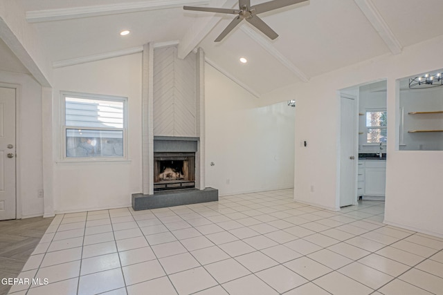 unfurnished living room with ceiling fan, a fireplace, vaulted ceiling with beams, sink, and light tile patterned floors