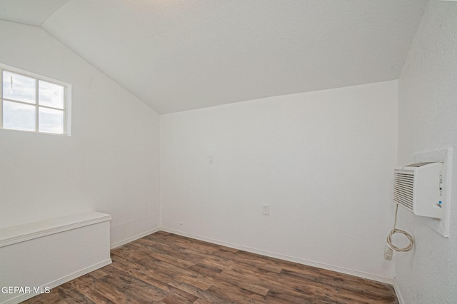 bonus room featuring dark wood-type flooring, a wall mounted AC, and vaulted ceiling