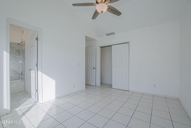 unfurnished bedroom featuring ceiling fan, lofted ceiling, ensuite bath, light tile patterned flooring, and a closet