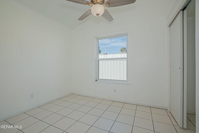 unfurnished bedroom featuring ceiling fan, light tile patterned floors, vaulted ceiling, and a closet