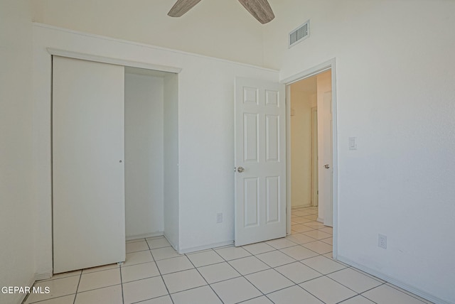 unfurnished bedroom featuring ceiling fan, light tile patterned flooring, and a closet