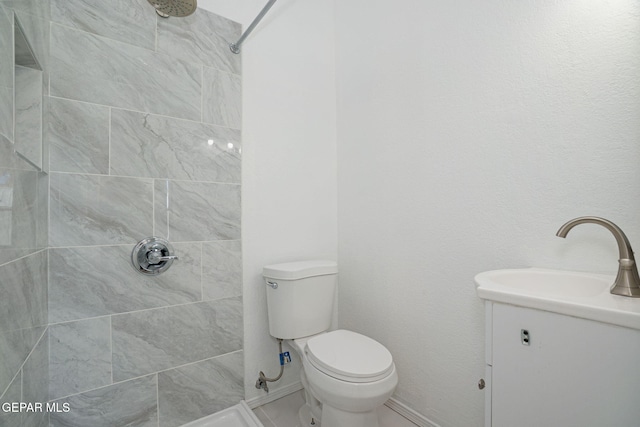 bathroom with toilet, vanity, and a tile shower