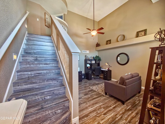 interior space with ceiling fan, a high ceiling, and hardwood / wood-style floors