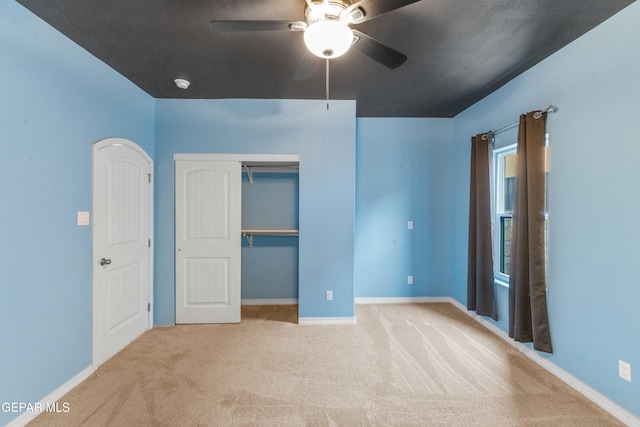 unfurnished bedroom featuring ceiling fan, a closet, and light carpet