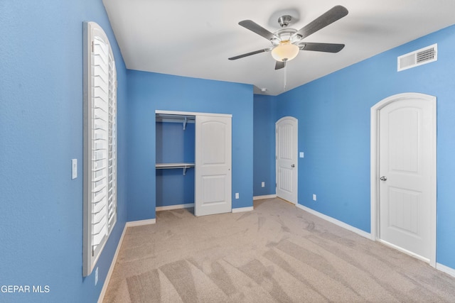 unfurnished bedroom featuring ceiling fan, light colored carpet, and a closet