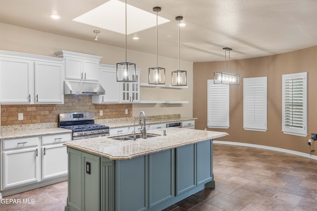 kitchen featuring sink, a kitchen island with sink, stainless steel gas range, white cabinets, and light stone counters