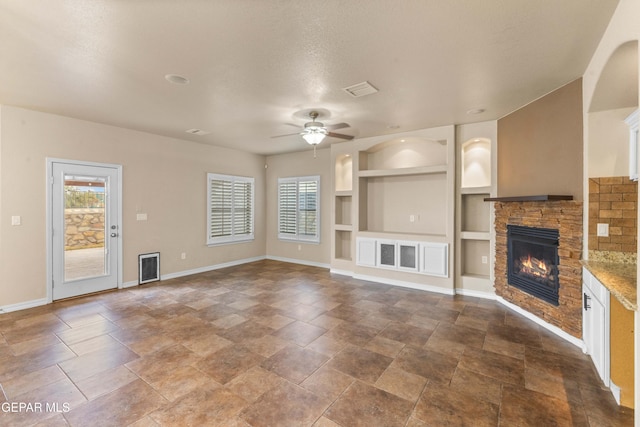 unfurnished living room with a textured ceiling, a fireplace, built in features, and ceiling fan