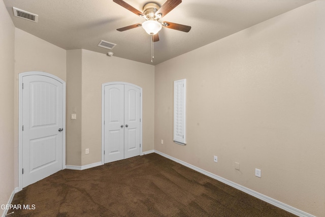 unfurnished bedroom with ceiling fan and dark carpet