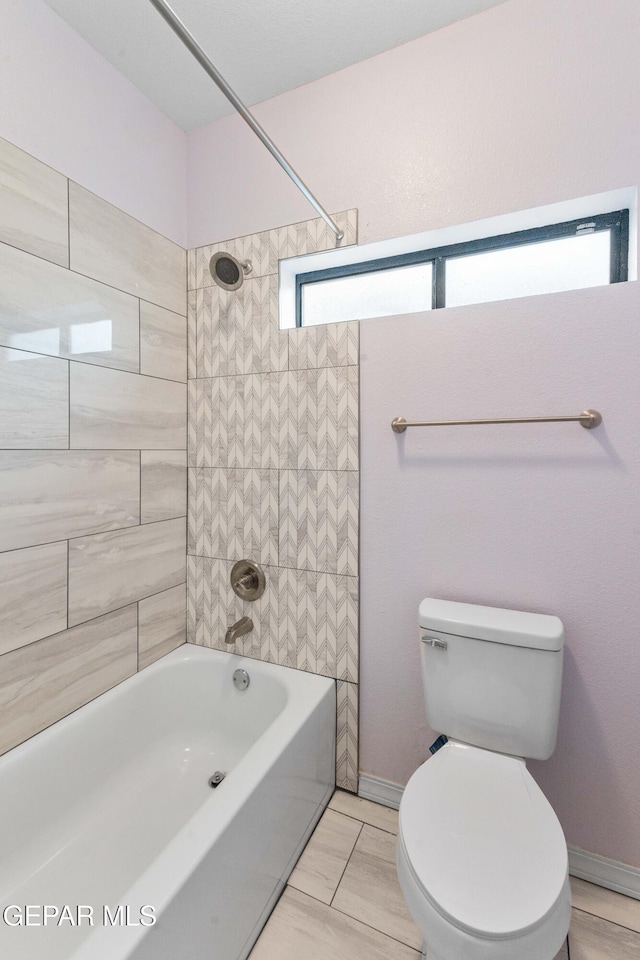 bathroom featuring toilet and tiled shower / bath