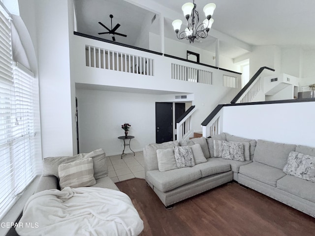 tiled living room featuring ceiling fan with notable chandelier and a towering ceiling