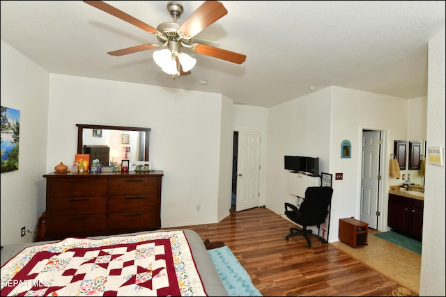 bedroom with ensuite bath, dark wood-type flooring, and ceiling fan