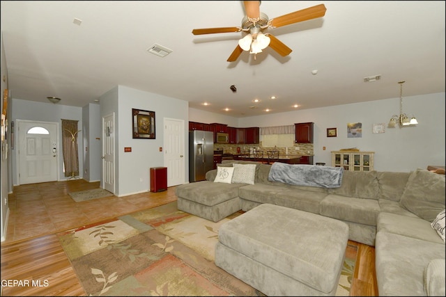 tiled living room with ceiling fan with notable chandelier