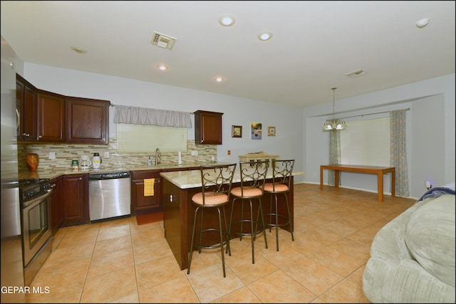 kitchen featuring pendant lighting, stainless steel appliances, a kitchen island, and backsplash