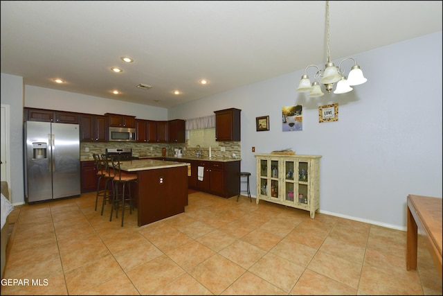 kitchen with a breakfast bar, a center island, hanging light fixtures, appliances with stainless steel finishes, and backsplash