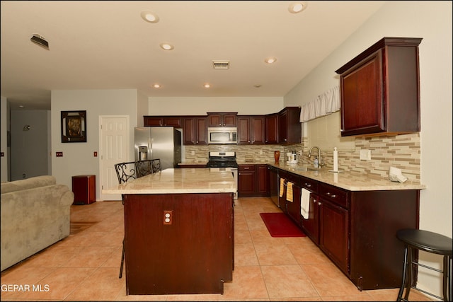 kitchen featuring tasteful backsplash, a center island, stainless steel appliances, and a breakfast bar