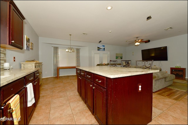 kitchen with hanging light fixtures, light tile patterned floors, a breakfast bar, and a kitchen island