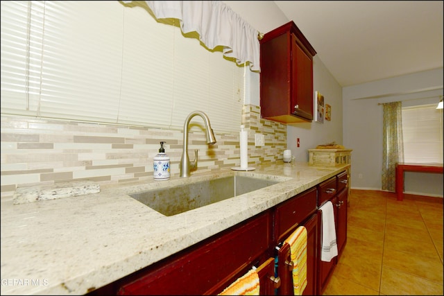 kitchen with light tile patterned flooring, light stone countertops, sink, and decorative backsplash