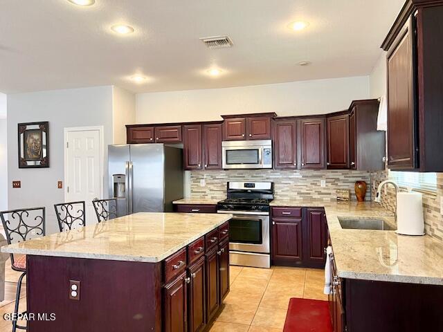 kitchen with sink, a kitchen breakfast bar, a kitchen island, stainless steel appliances, and backsplash