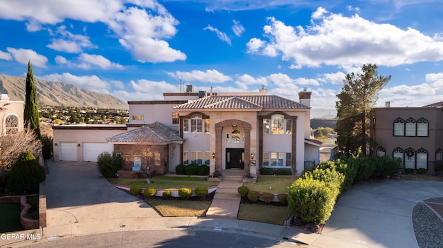 mediterranean / spanish house featuring a front yard, a mountain view, and a garage